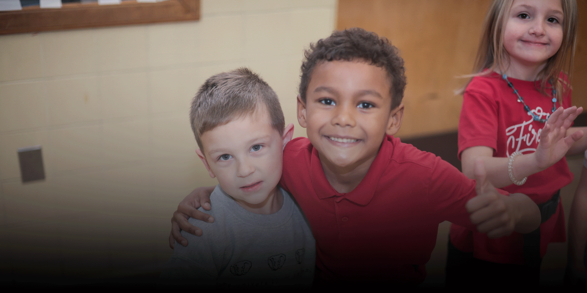 Three students smiling and posing together, one giving a thumbs up.